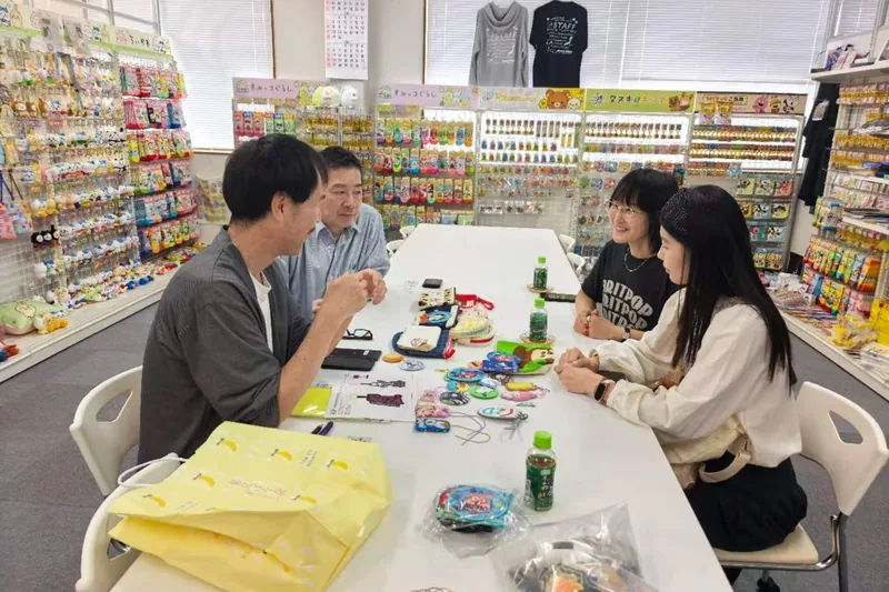 Buyer meeting at an international trade show, working through patch and keychain samples at the table