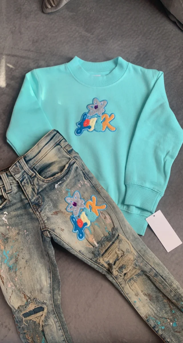 Mint green crewneck sweatshirt with custom knee-patch distressed denim jeans