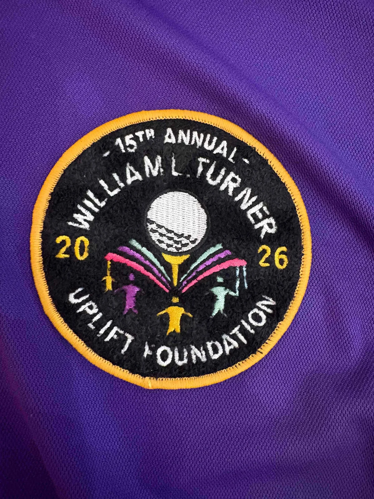 Circular embroidered patch sewn onto purple fabric