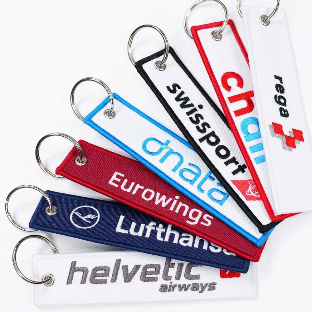 Embroidered flight tag keychains with metal key rings, shown in a fan arrangement